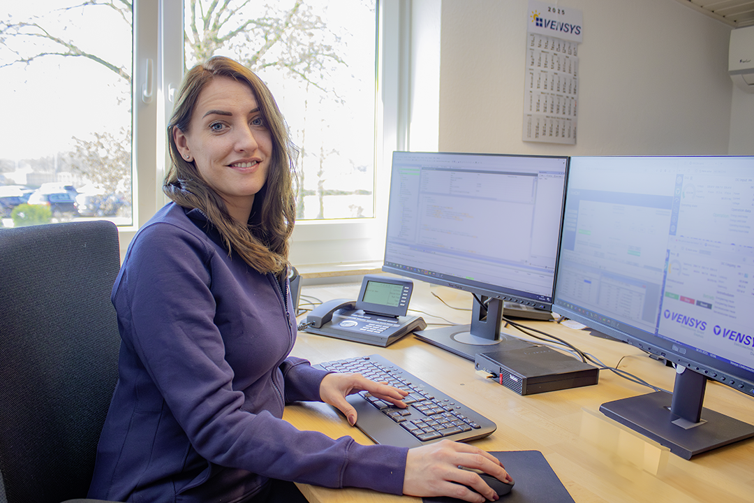 Eine Mitarbeiterin sitzt an ihrem Schreibtisch im Büro